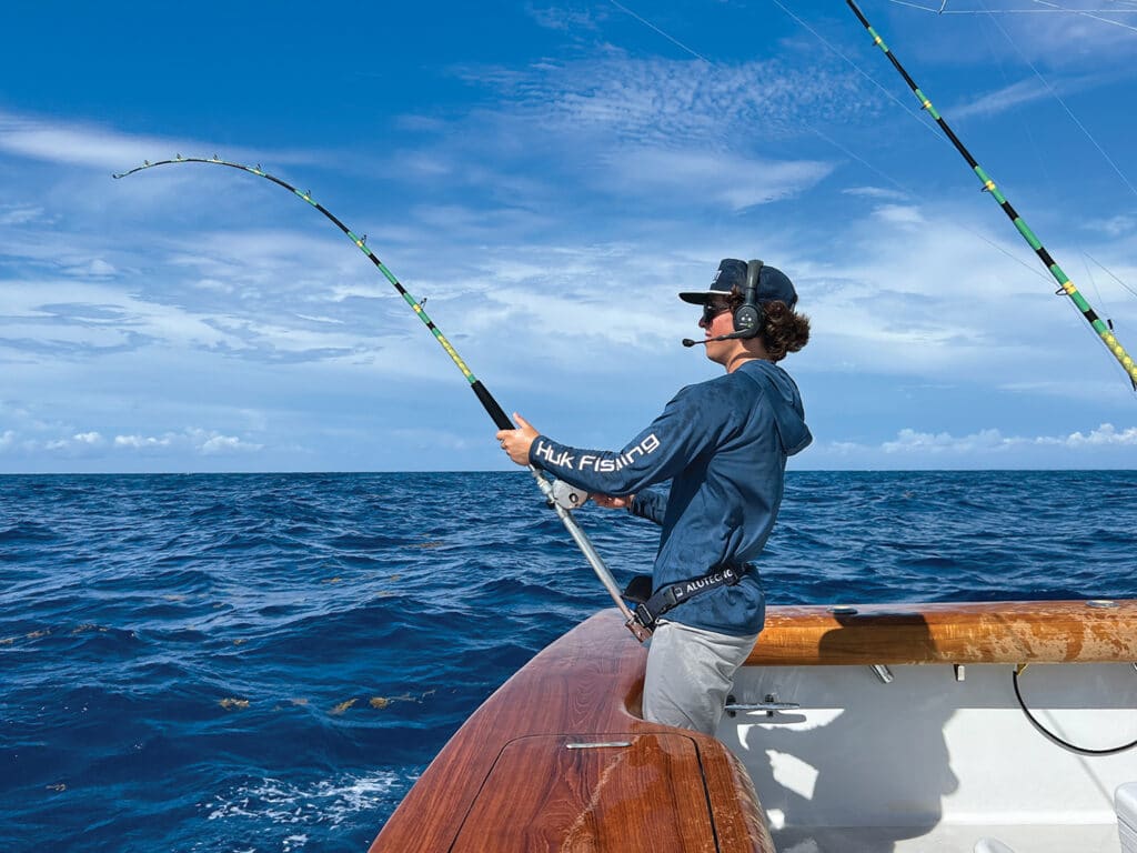 A young angler casting a line out from the cockpit of a sport-fishing boat.