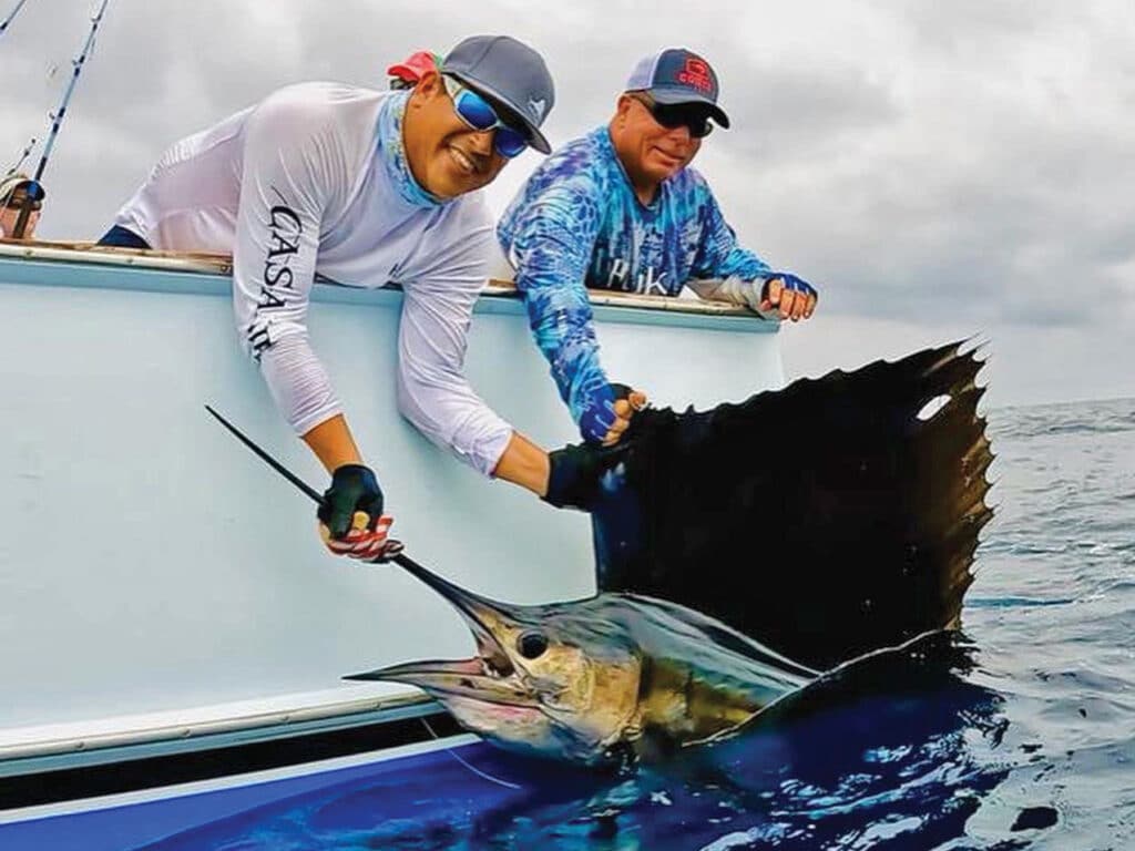 Anglers pull a large Pacific sailfish boatside.