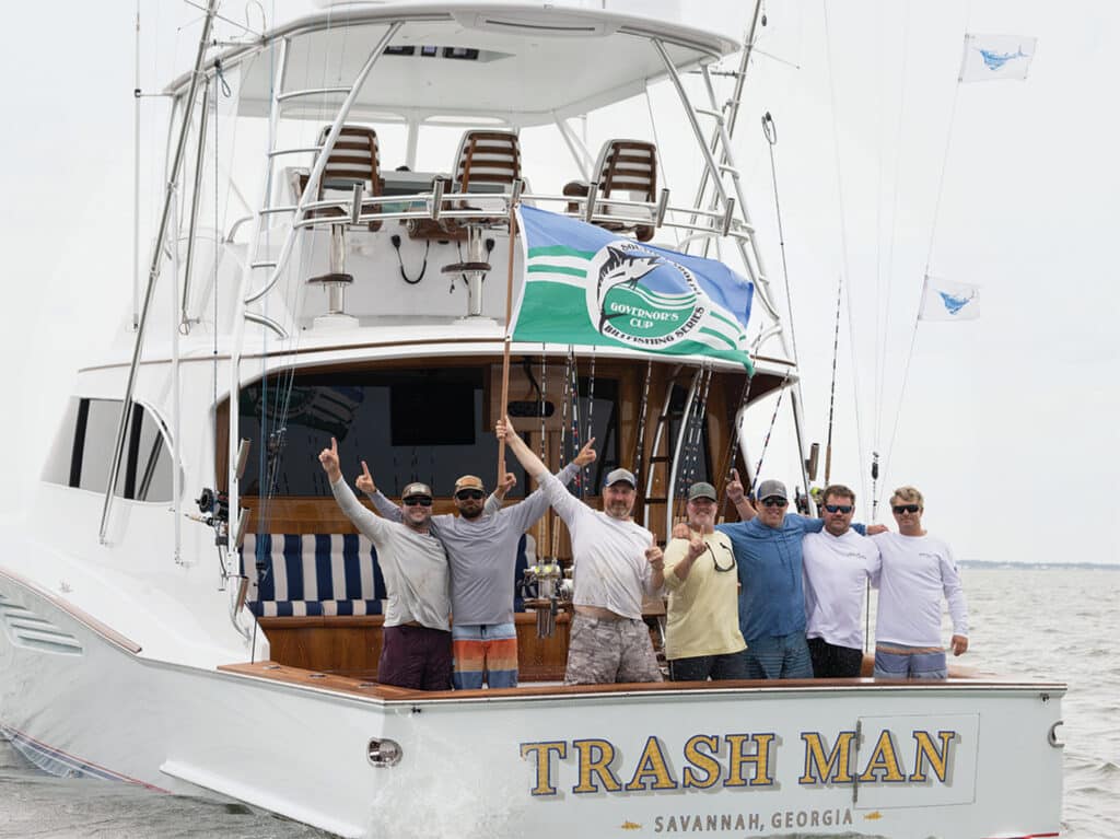 A sport-fishing team celebrate in the transom of their sport-fishing boat.