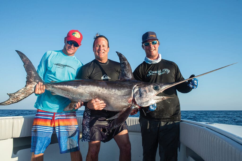 Three anglers hold up a swordfish.
