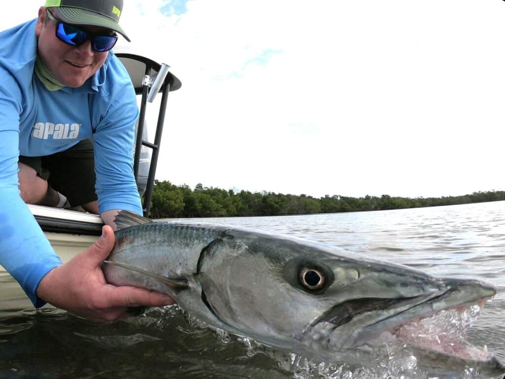 An angler pulling a barracuda from the water.