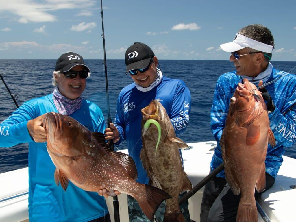Three anglers holding up grouper