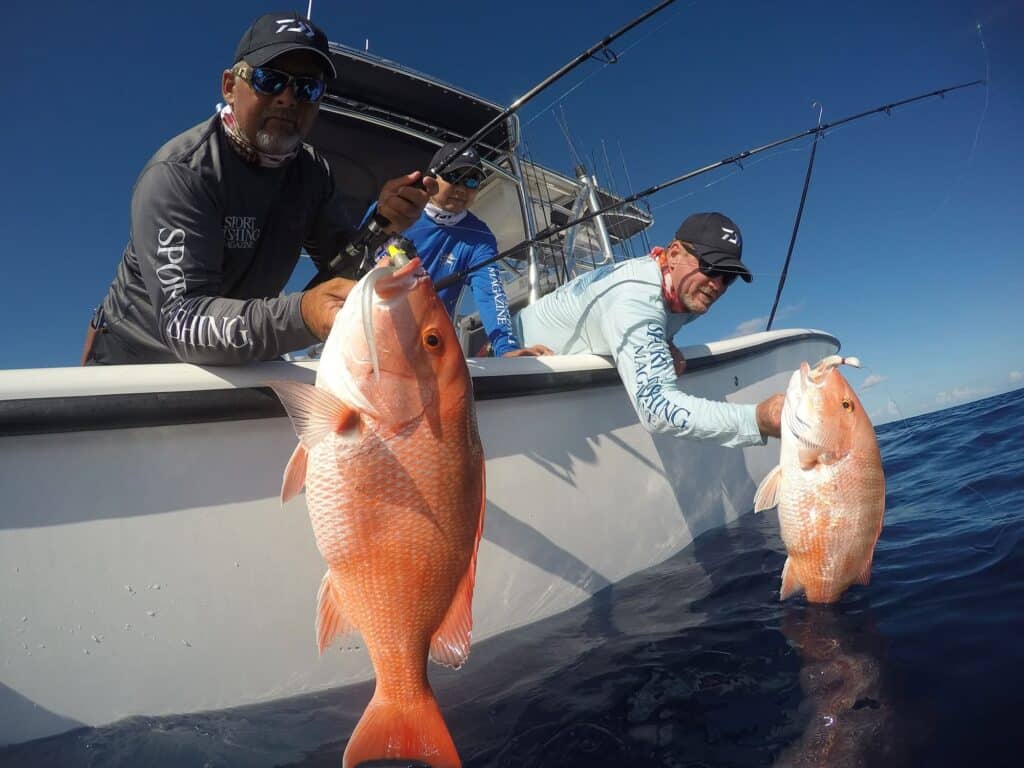 Three anglers pulling red snapper from the water.