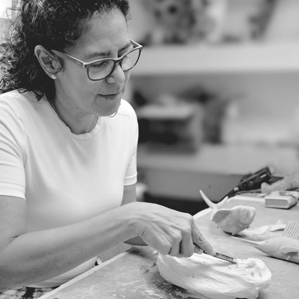 A black and white image of an artist creating a mold for a casting of a tournament trophy.