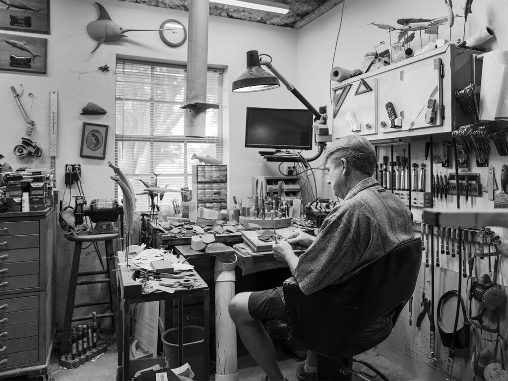A black and white image of Chris Costello working at his workshop.