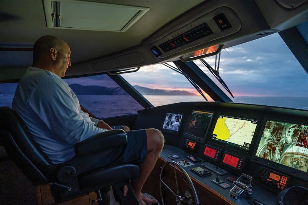 A boat captain oversees the helm of a sport-fishing boat and monitors the digital displays
