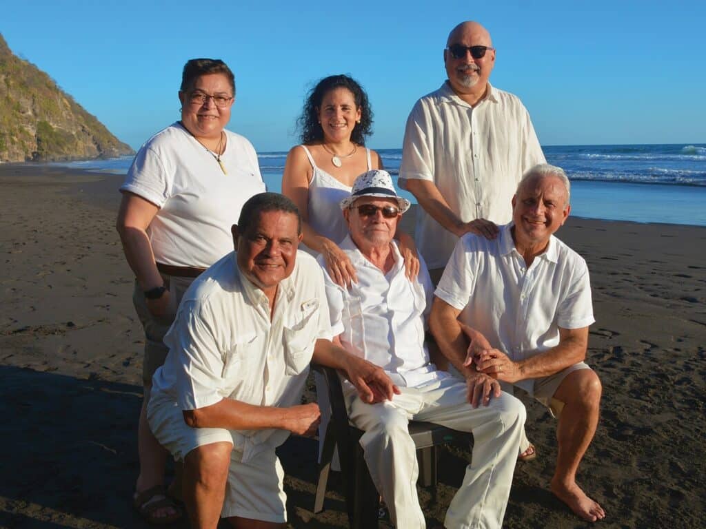 The Panameño family posing on the beach, six people stand in front of the shore line.