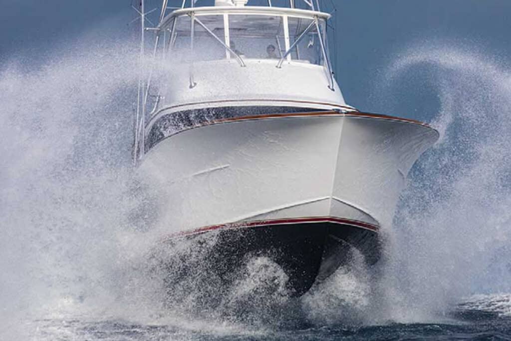 Waves crashing against the hull of a sport-fishing boat as it cruises through the water at high speeds.