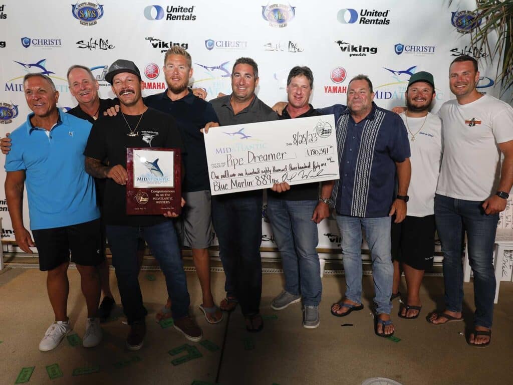 A team of sport-fishing anglers hold up awards and an oversized check at The MidAtlantic awards ceremony