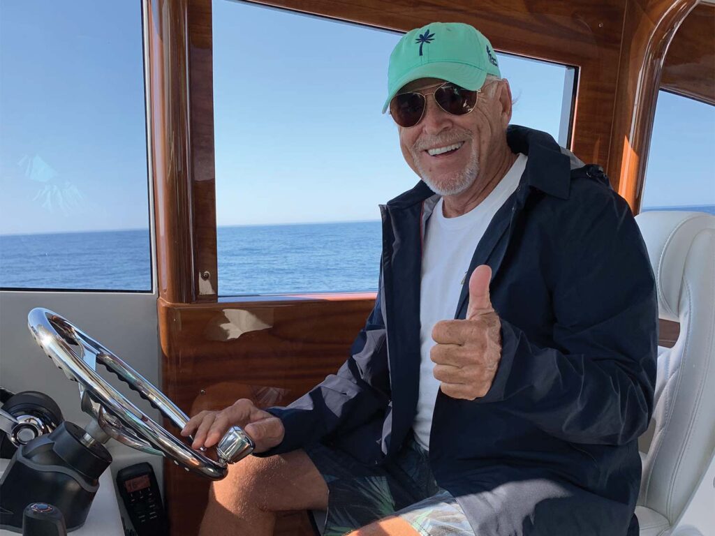 Jimmy Buffett giving a thumbs up at the helm.