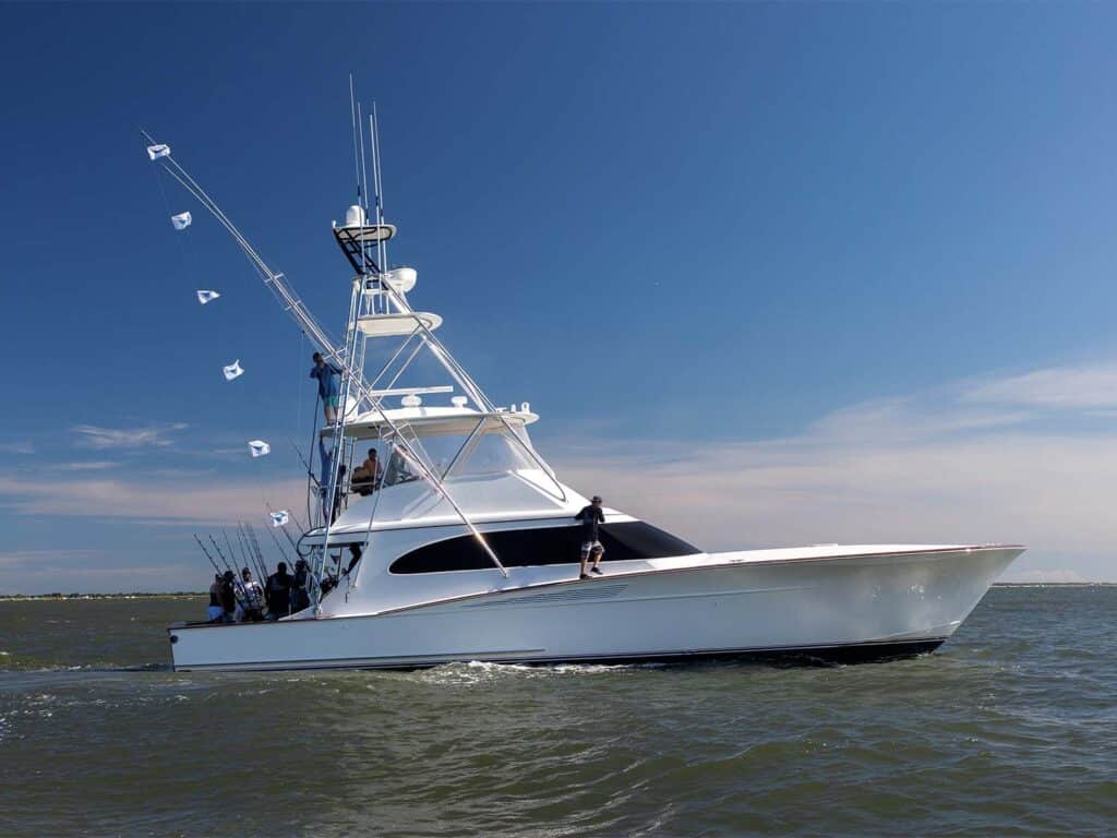 A sport-fishing boat on the water during a beautiful clear day. Release flags can be seen flying from its rigging.