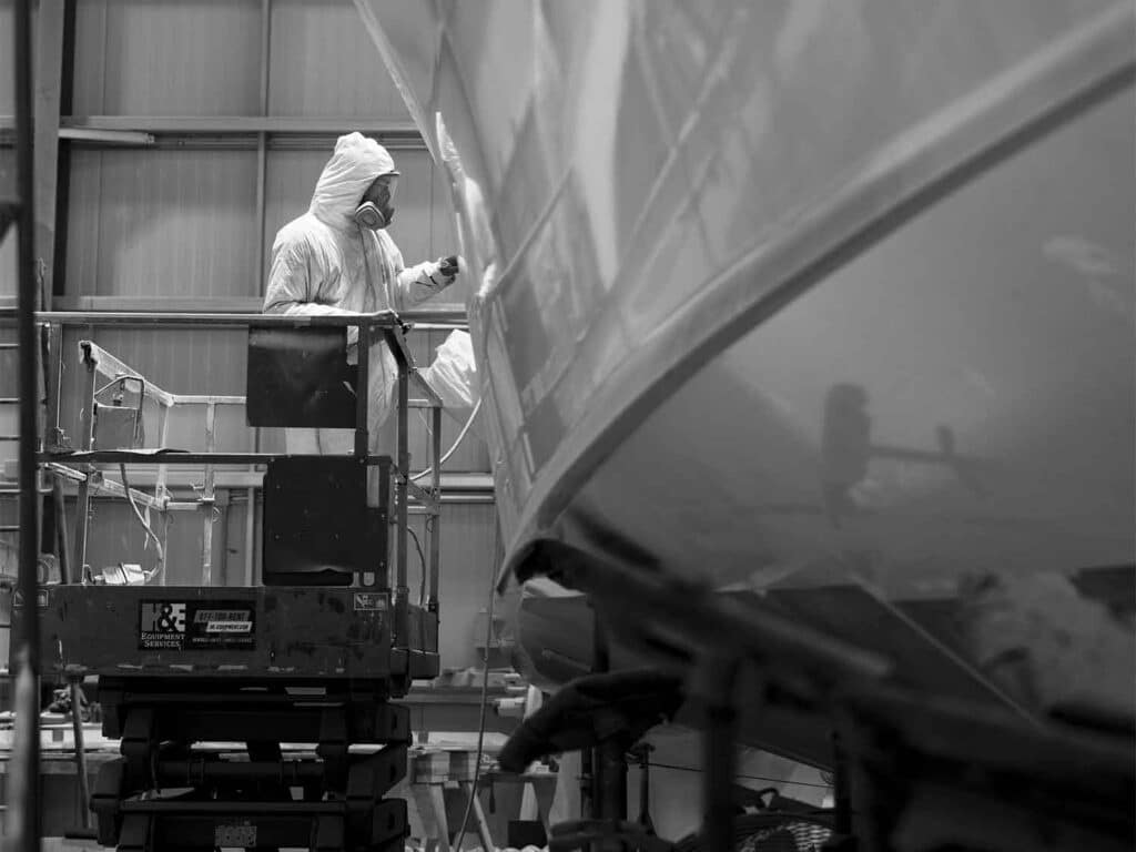 Black and white image of a crewmate working on the hull of a Duffie Boatworks custom boat.