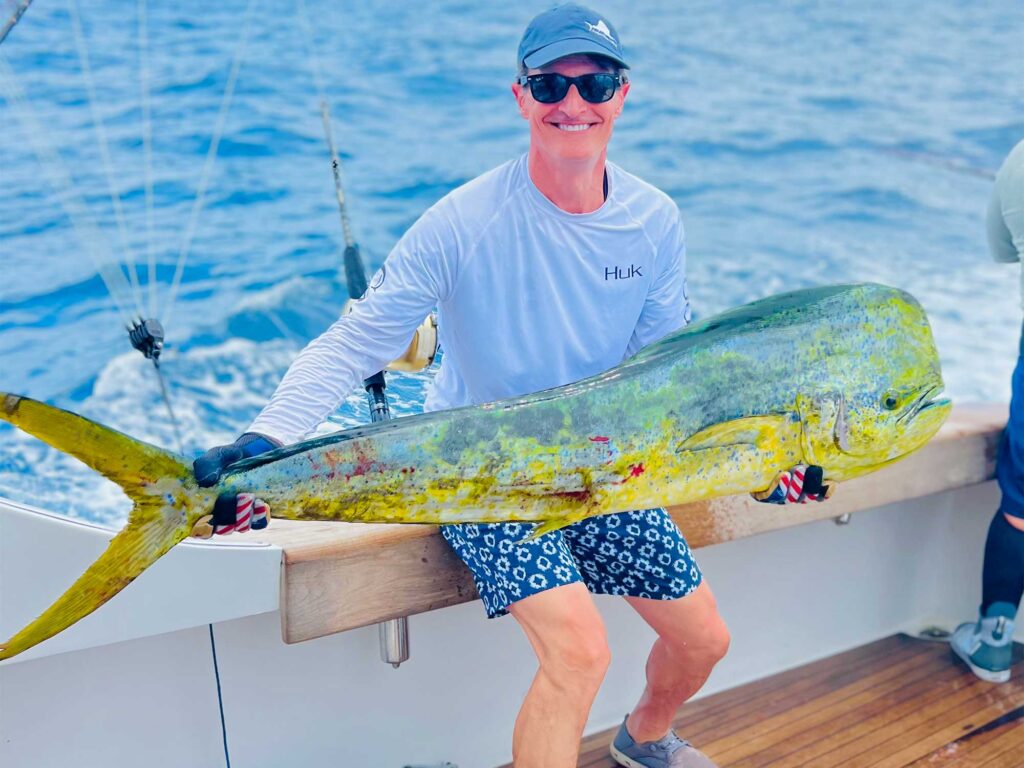 A sport-fishing angler holds up a large dorado caught on a fishing expediton.