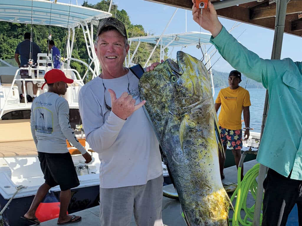 A man holding up a dorado fish.