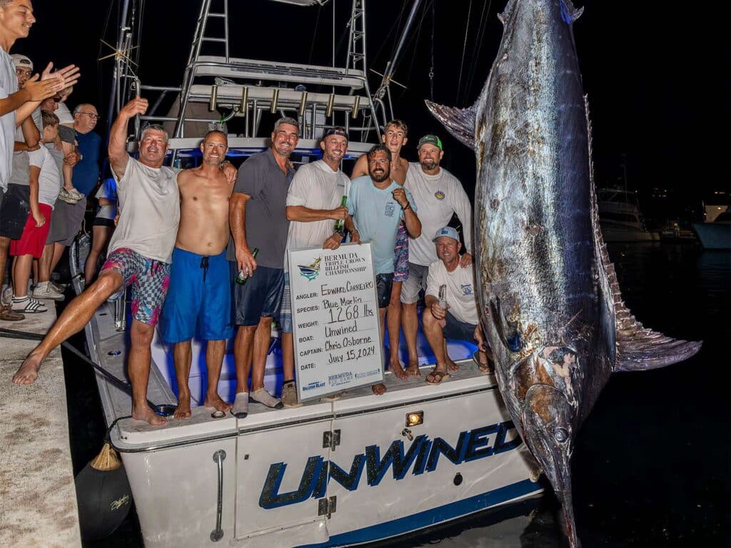 a group of people posing for a picture with a large marlin on a boat