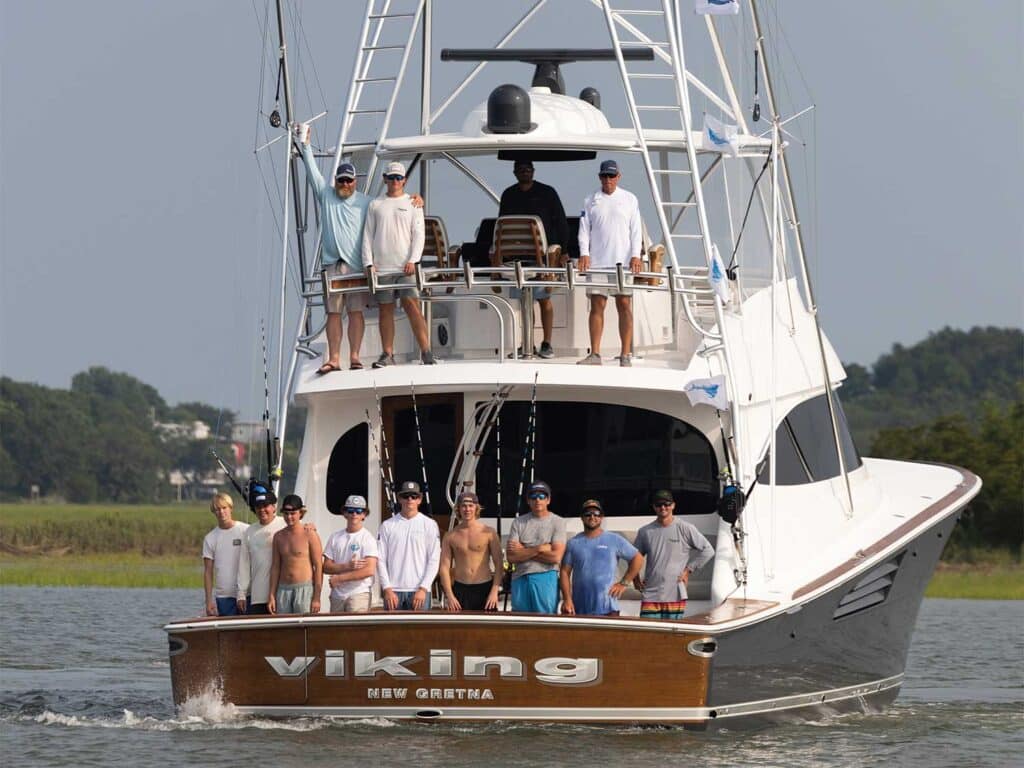 View of a sport-fishing boat with anglers standing in the cockpit and tower.