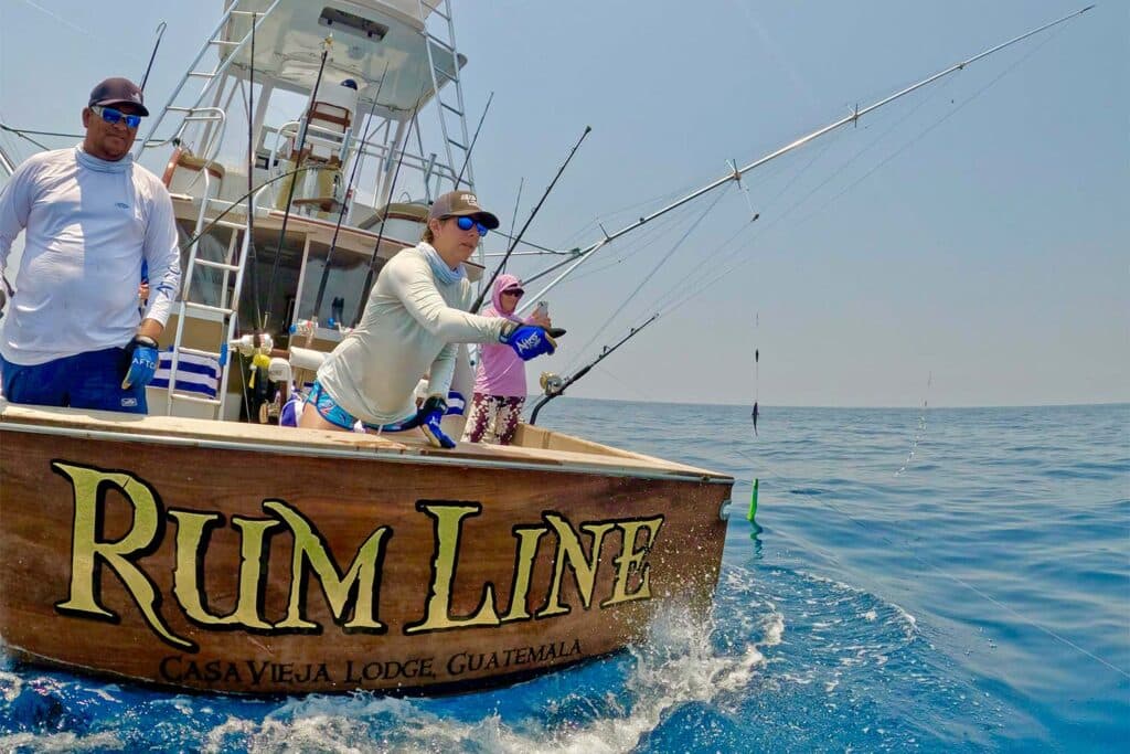 View of the cockpit of a sport-fishing boat with a lady angler casting out into the ocean.