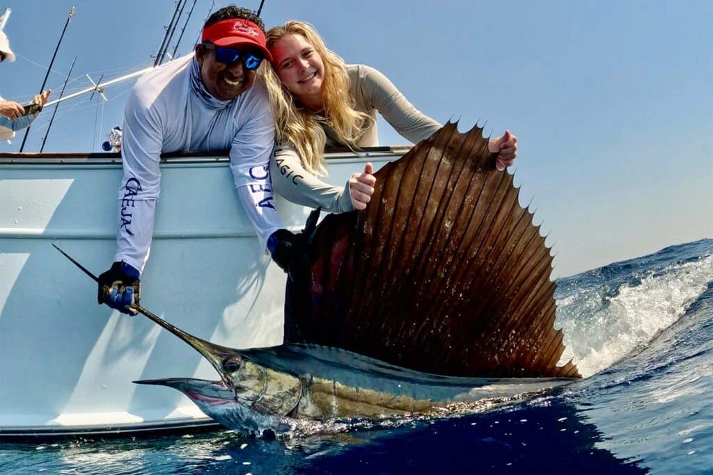 A crew and anglers pull a sailfish boatside.