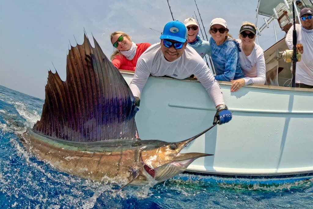 A crew and anglers pull a sailfish boatside.