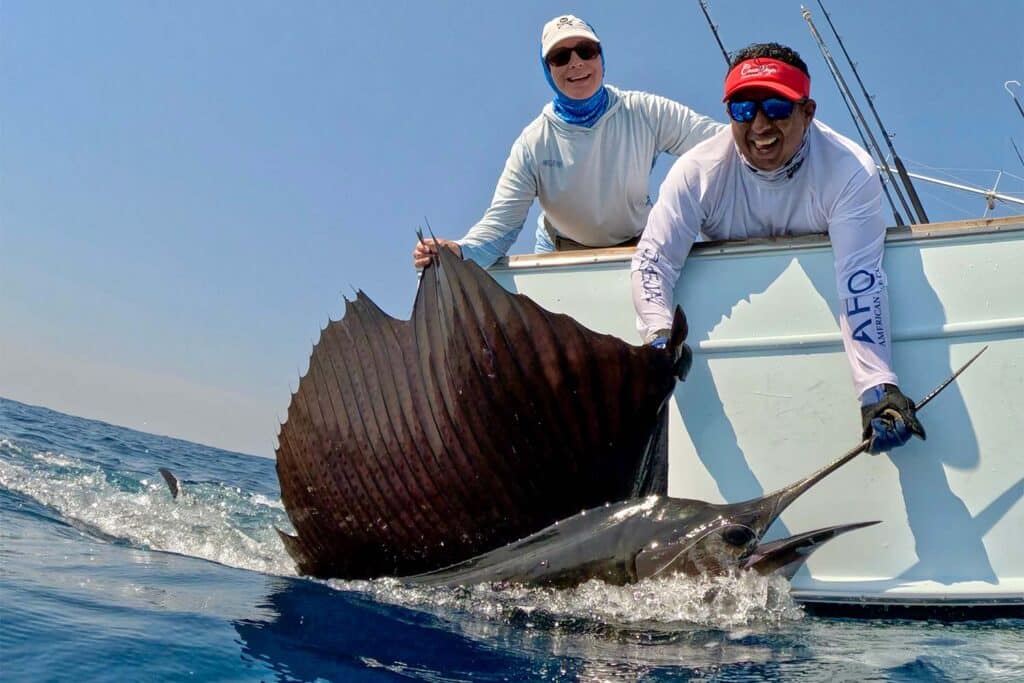 A crew and anglers pull a sailfish boatside.