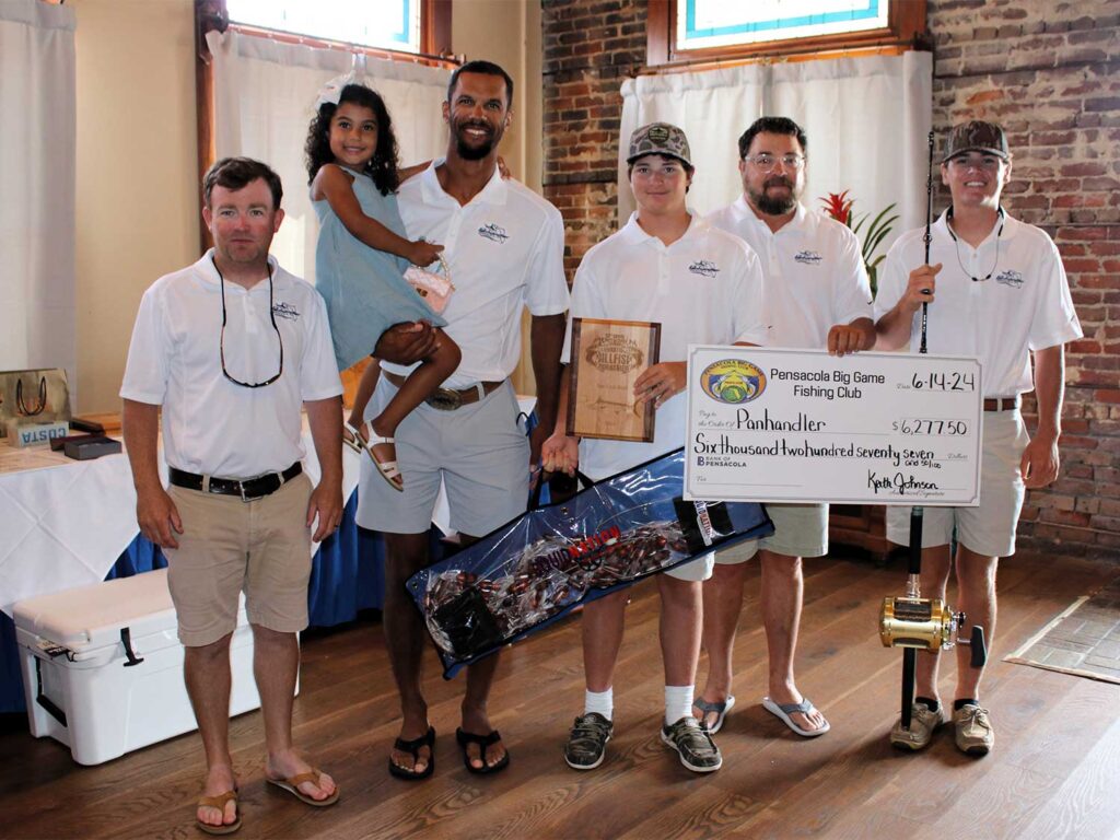 The Panhandler team stands posing for the camera. They hold an oversized check.