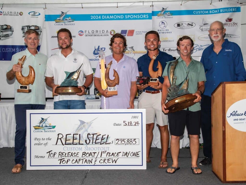 Team Sandman standing at an awards ceremony holding their trophies and oversized check.