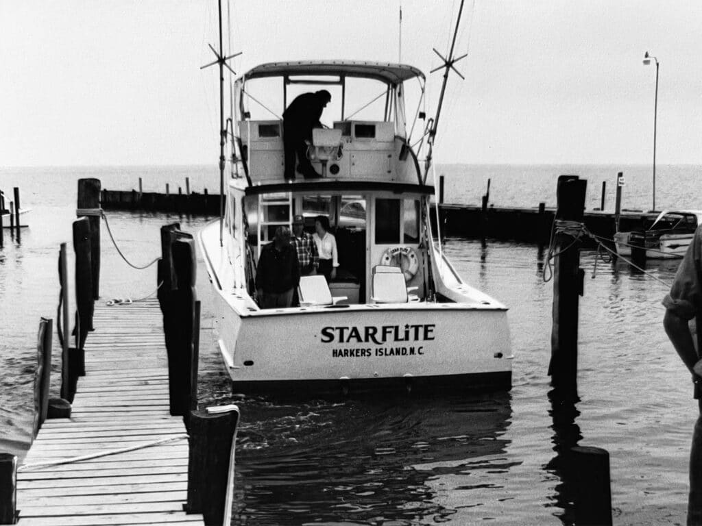Black and white image of a small boat docked in a marina.