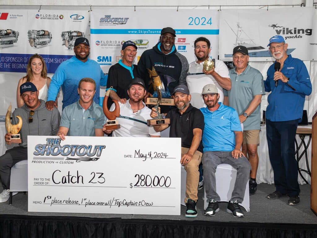 Michael Jordan and Team Catch 23 standing at an awards ceremony holding their trophies and oversized check.