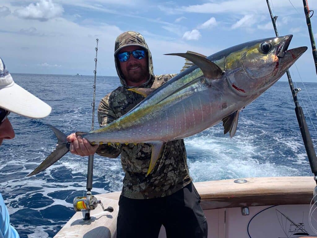 A sport-fishing angler holds up a large tuna.