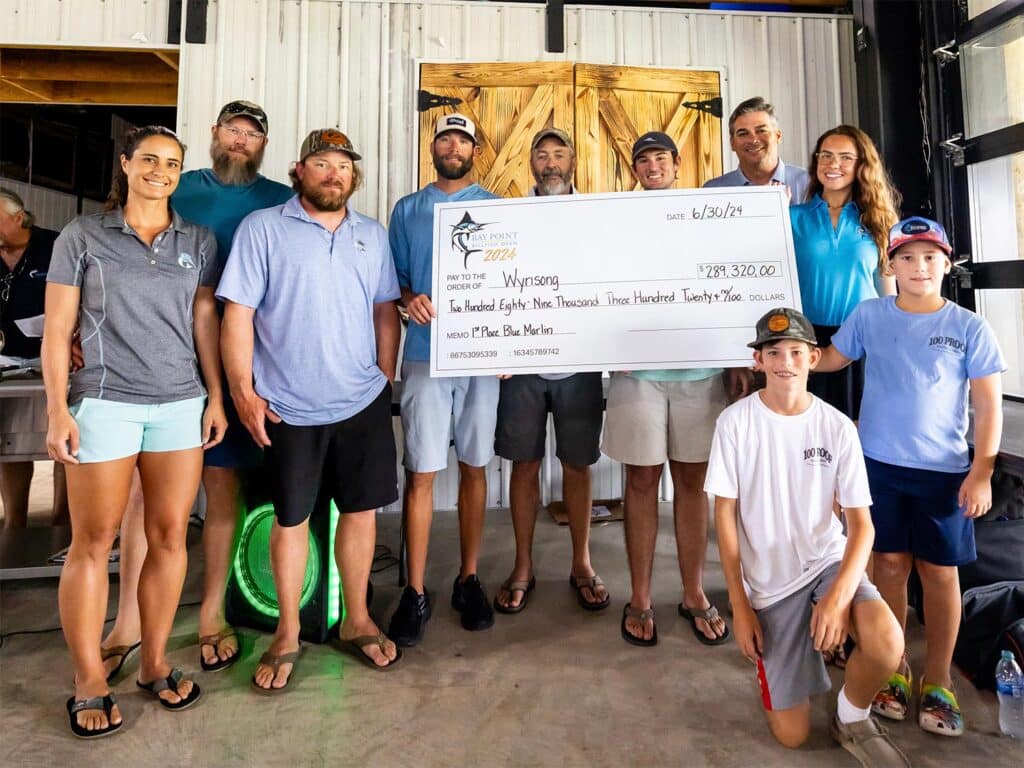 Team Wynsong stands at the awards ceremony, celebratorily holding up an oversized check.