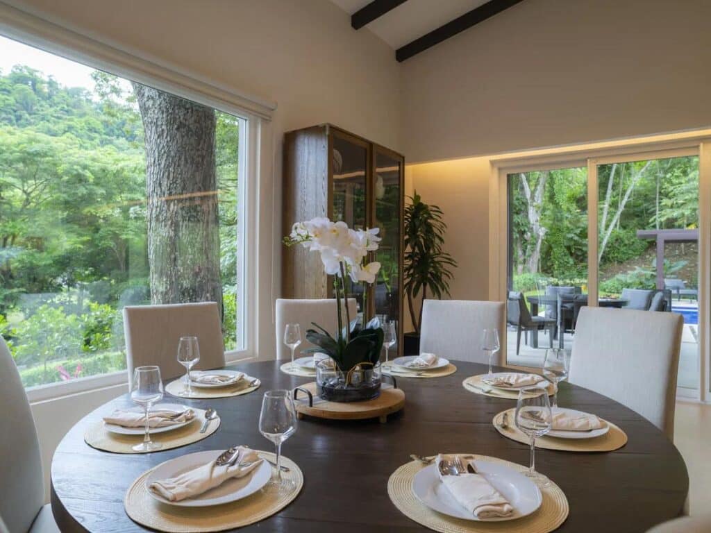 A round dining table arranged with white plates, napkins, and flowers.