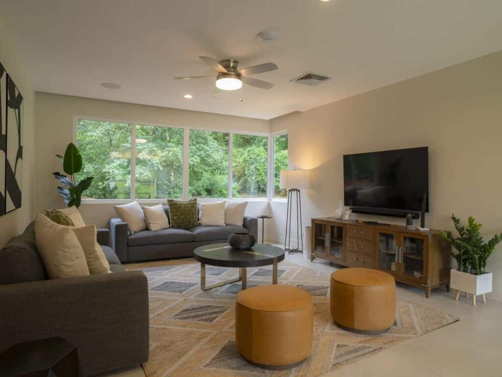 View of the interior of a Casa Selva Tica dwelling. Glass windows cover the side of a wall showing the vibrant, lush outdoors beyond.
