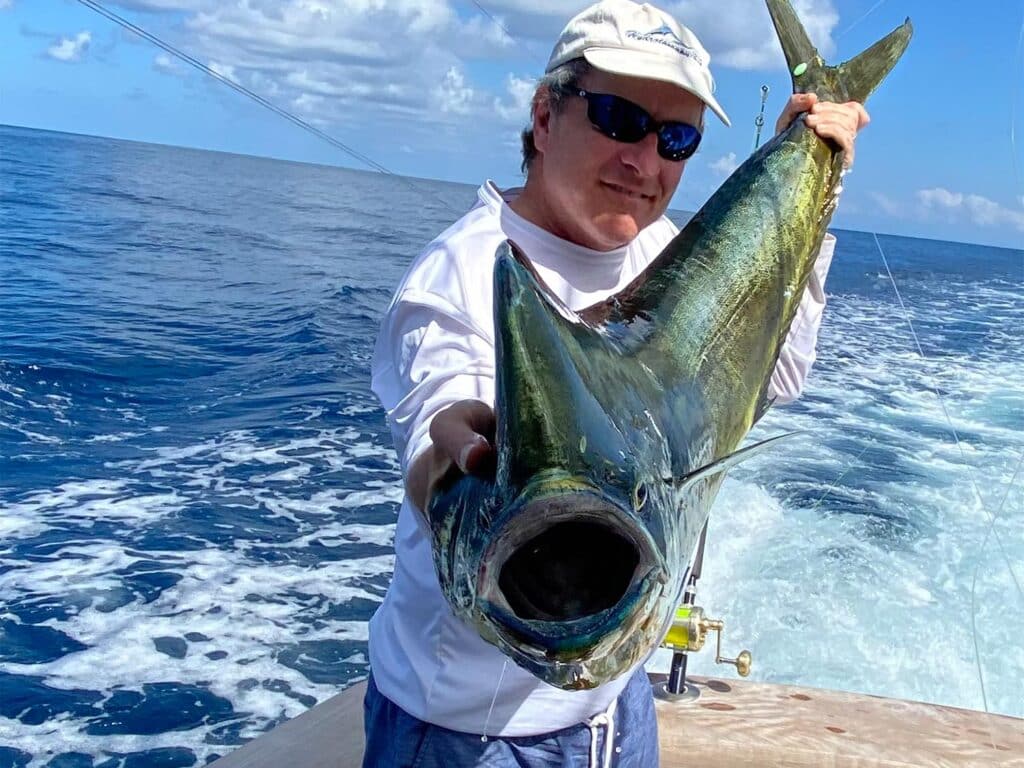 Angler holds up a dorado towards the camera.