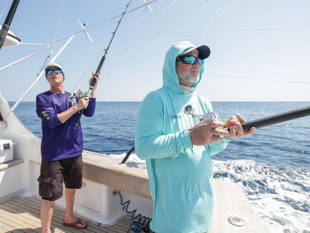 Two anglers fishing from the cockpit of a sport-fishing boat.