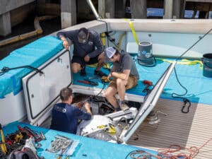 carbon fiber sailboat hull Three boat crew administering repairs to a sport-fishing boat via a hatch opening in the cockpit. protective tarps are laid over the transom and hardwood of the cockpit's flooring.