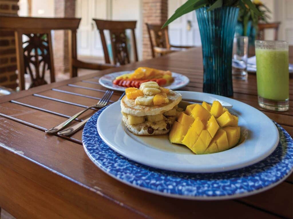 A plate of banana pancakes on an outdoor dining table.