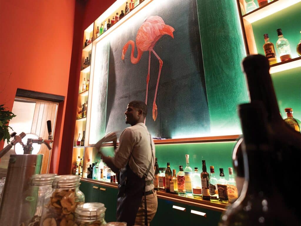 A bartender shaking a cocktail mixer behind the bar.