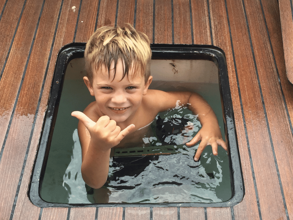 A young child sits in the baitwell of a sport-fishing boat.