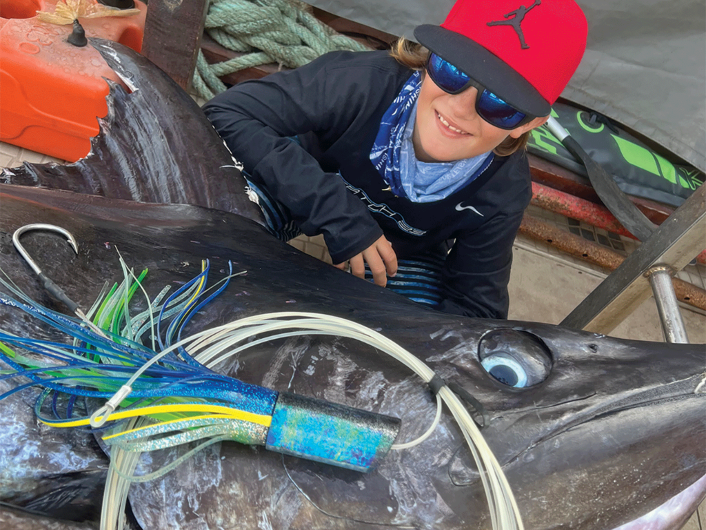 A young child next to a marlin.