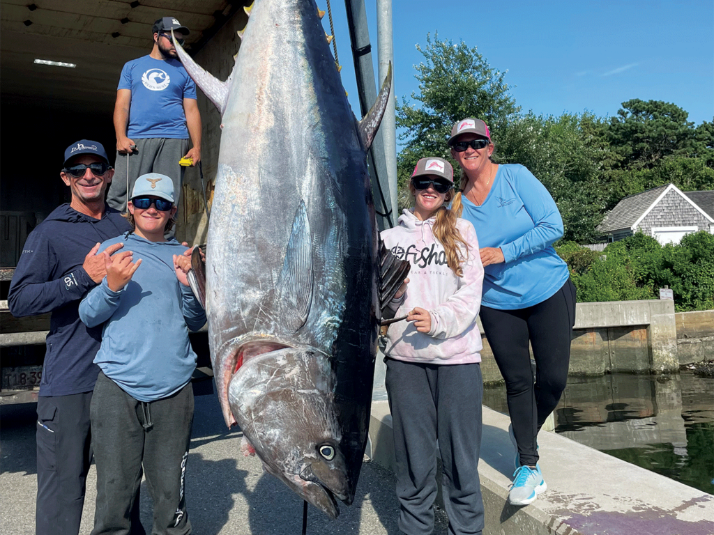 A fishing family stands next to a bluefin tuna.