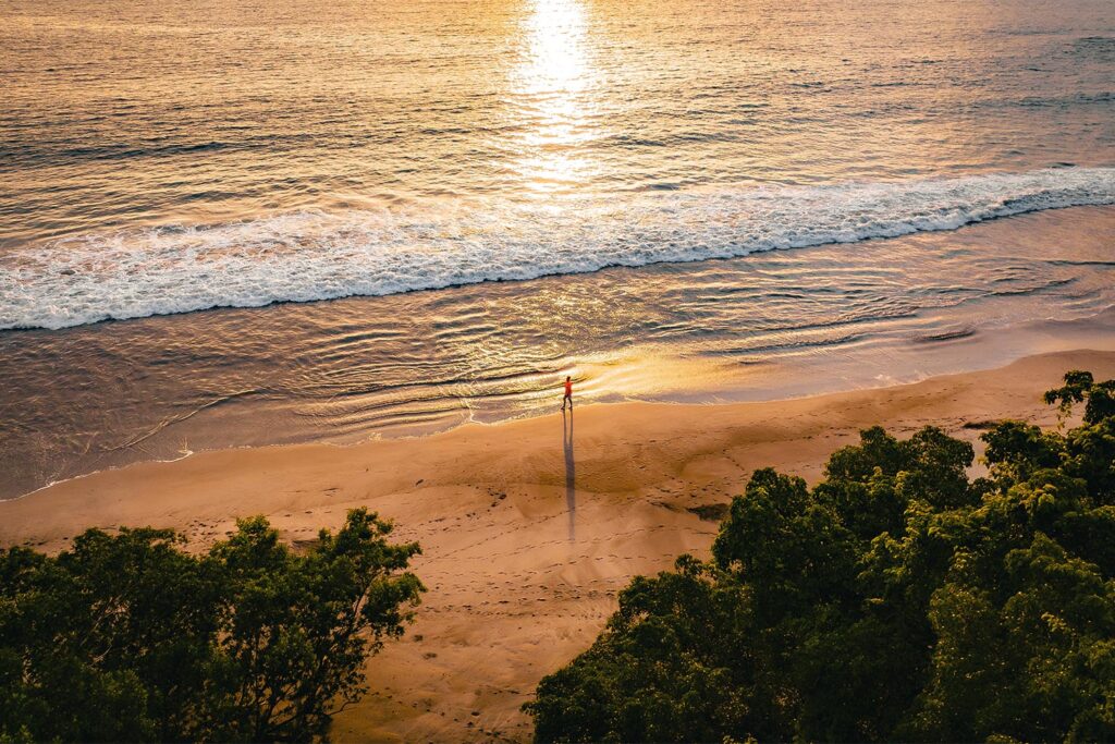 A lone person walks on the Marina Flamingo beaches at sunset