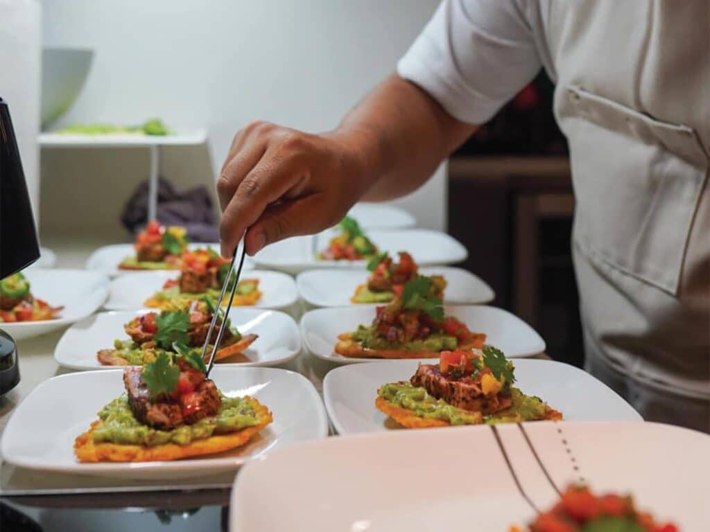 A chef puts finishing touches on prepared dinner.