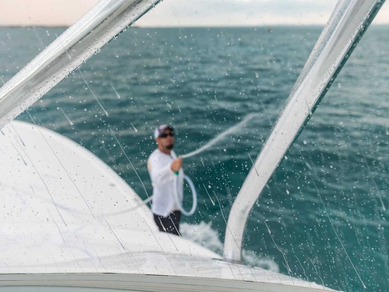 A crewmate cleaning off a boat's enclosure
