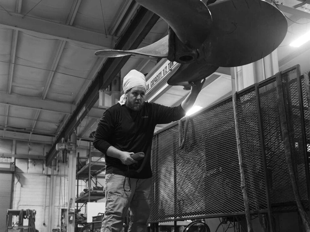 Black and white image of a technician working on a propeller.