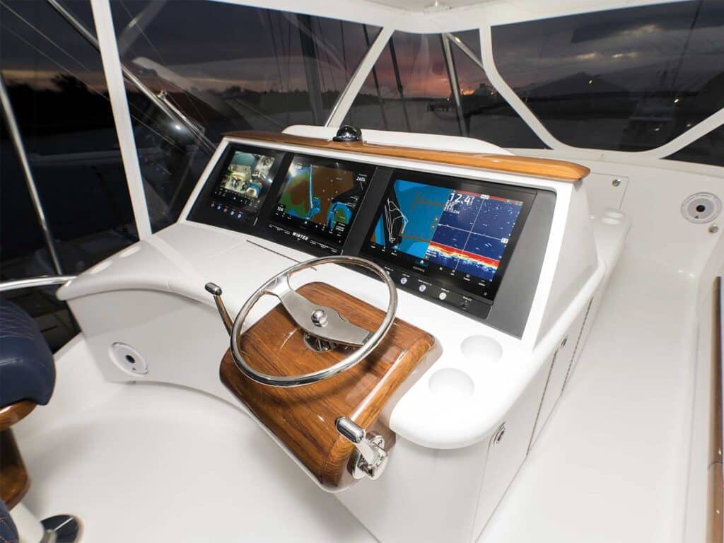 The flybridge of a sport-fishing boat outfitted with a steering wheel and digital displays for tracking and navigation.