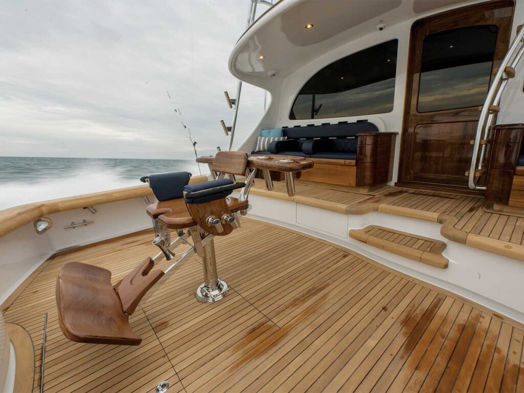 The cockpit of a sport-fishing boat outfitted with a fighting chair. behind the cockpit is mezzanine seating and a ladder.