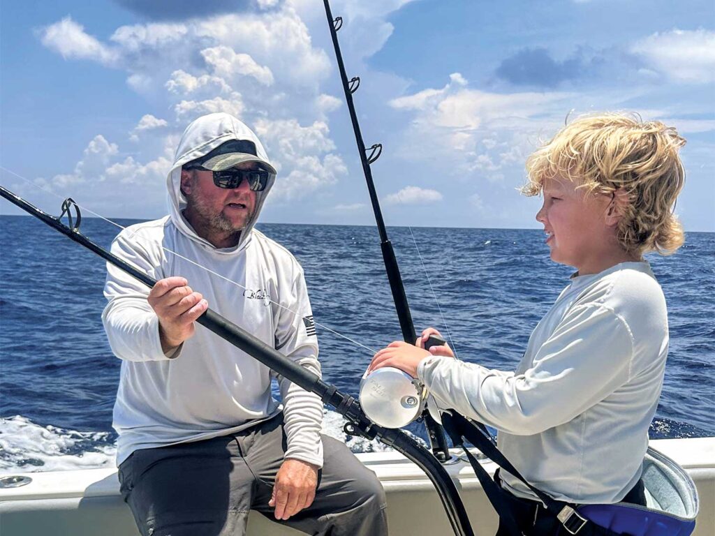 Bo Jenyns instructs his son in the cockpit of a sport-fishing boat.