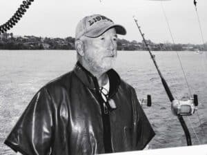 A black and white image of Capt. John Batterton at the helm of a sport-fishing boat.