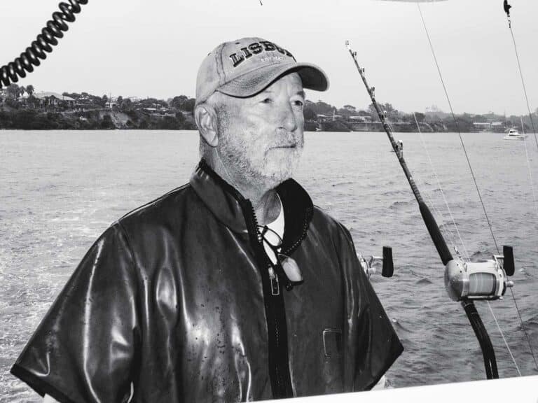 A black and white image of Capt. John Batterton at the helm of a sport-fishing boat.