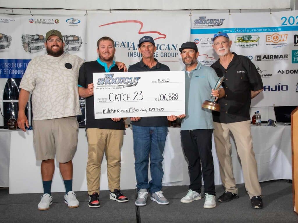 Team Catch 23 stands in celebration at the awards ceremony and holds an oversized check.